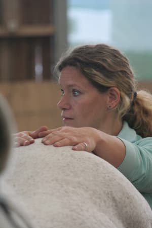 Sabine Brück legt die Hände auf den Rücken eines Pferdes